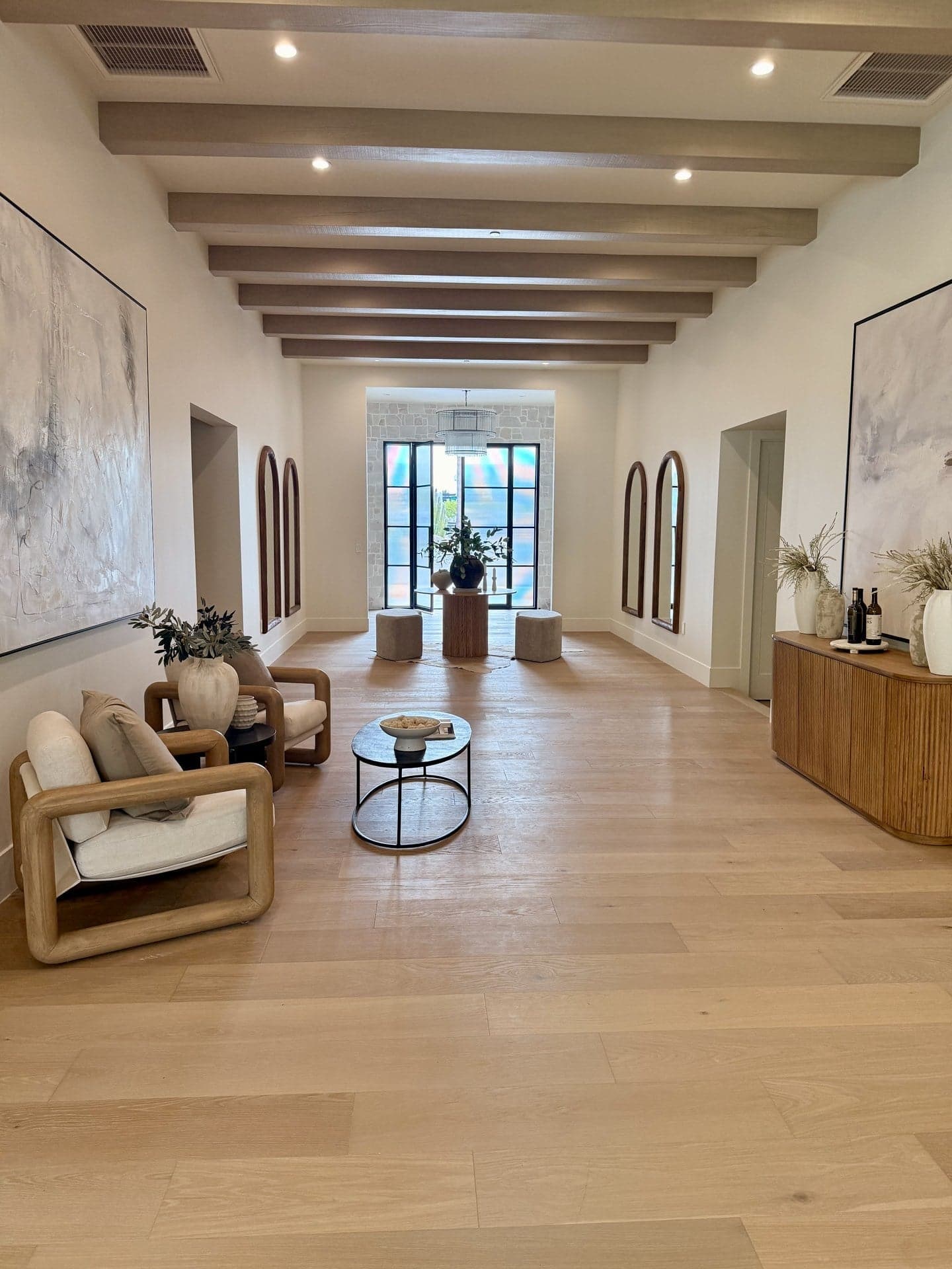 Finished entry foyer with exposed beams, oak floors, and arched mirrors