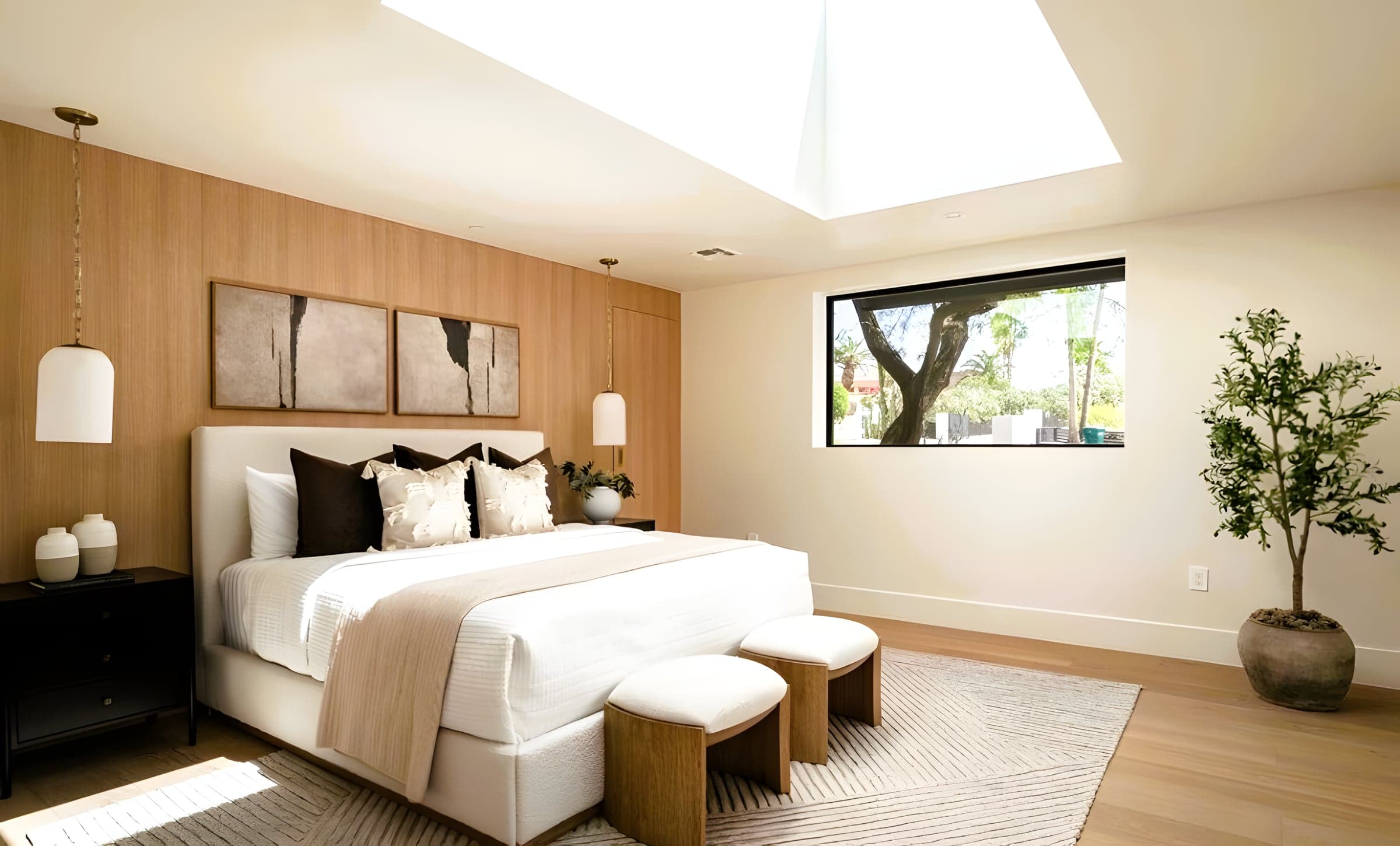 Finished primary bedroom with oak headboard wall and oversized skylight